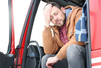 man with hand on his head sitting in cab of truck