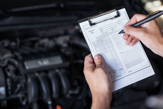 person checking list in front of vehicle engine