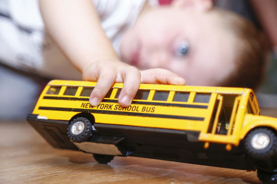 child playing with a toy school bus